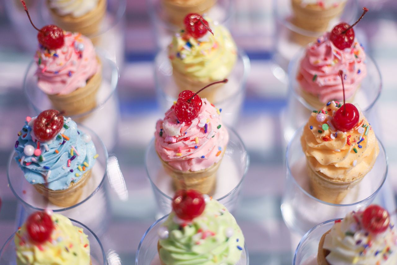 Vibrant cupcake cones topped with cherries and sprinkles, a festive sweet treat.
