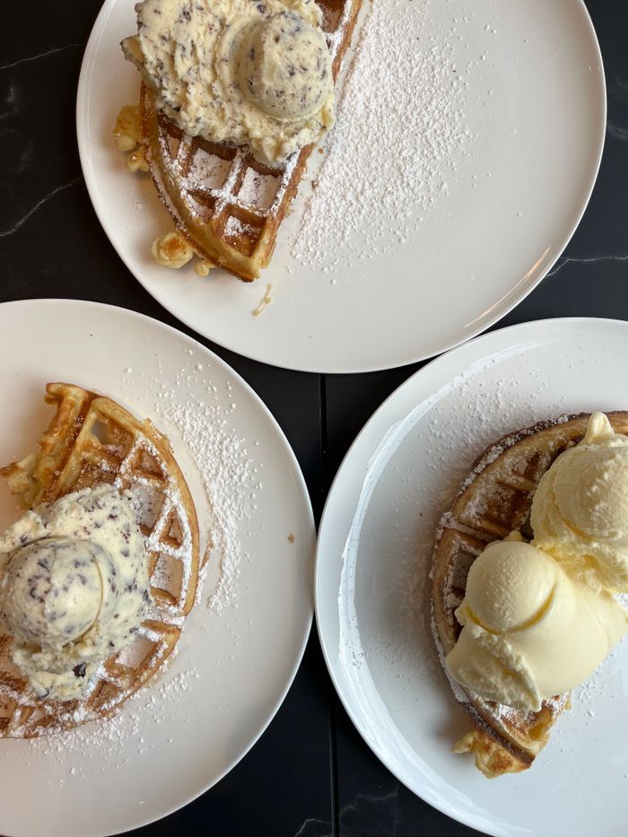 Tasty waffles topped with vanilla and chocolate ice cream served on white plates.