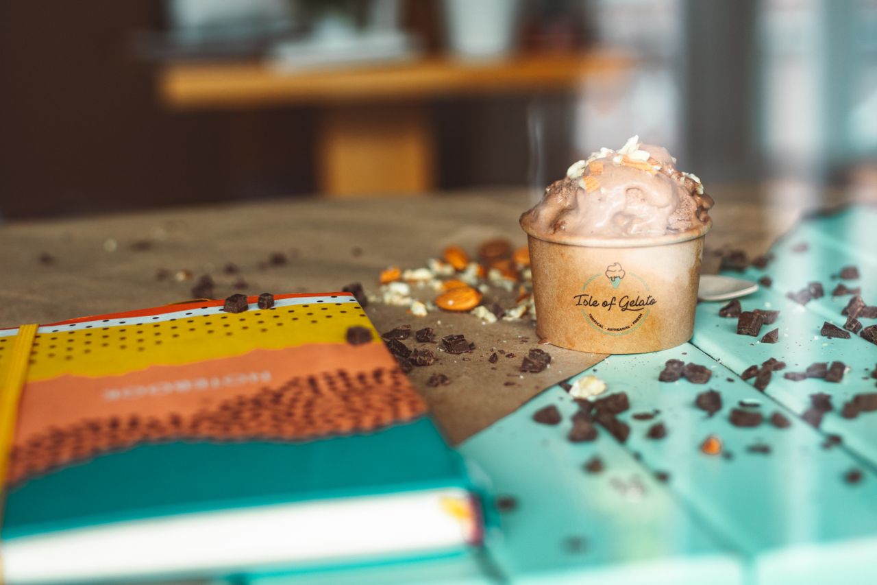 Delicious chocolate gelato in a paper cup with nuts and chocolate pieces.